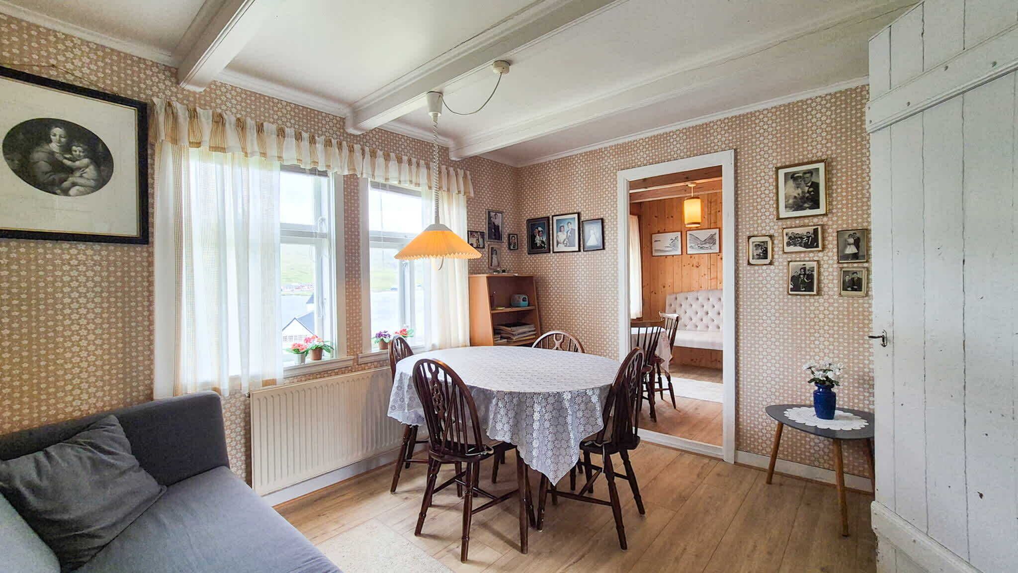 Un coin repas avec une table et des chaises, un canapé, un radiateur et une bibliothèque.