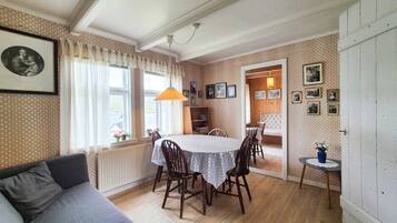 Un coin repas avec une table et des chaises, un canapé, un radiateur et une bibliothèque.