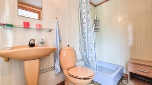 Une salle de bain équipée d’un lavabo, de toilettes, d’une baignoire et d’un rideau de douche.