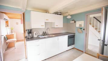 A compact kitchen with white cabinets, a built-in oven, and a sink.