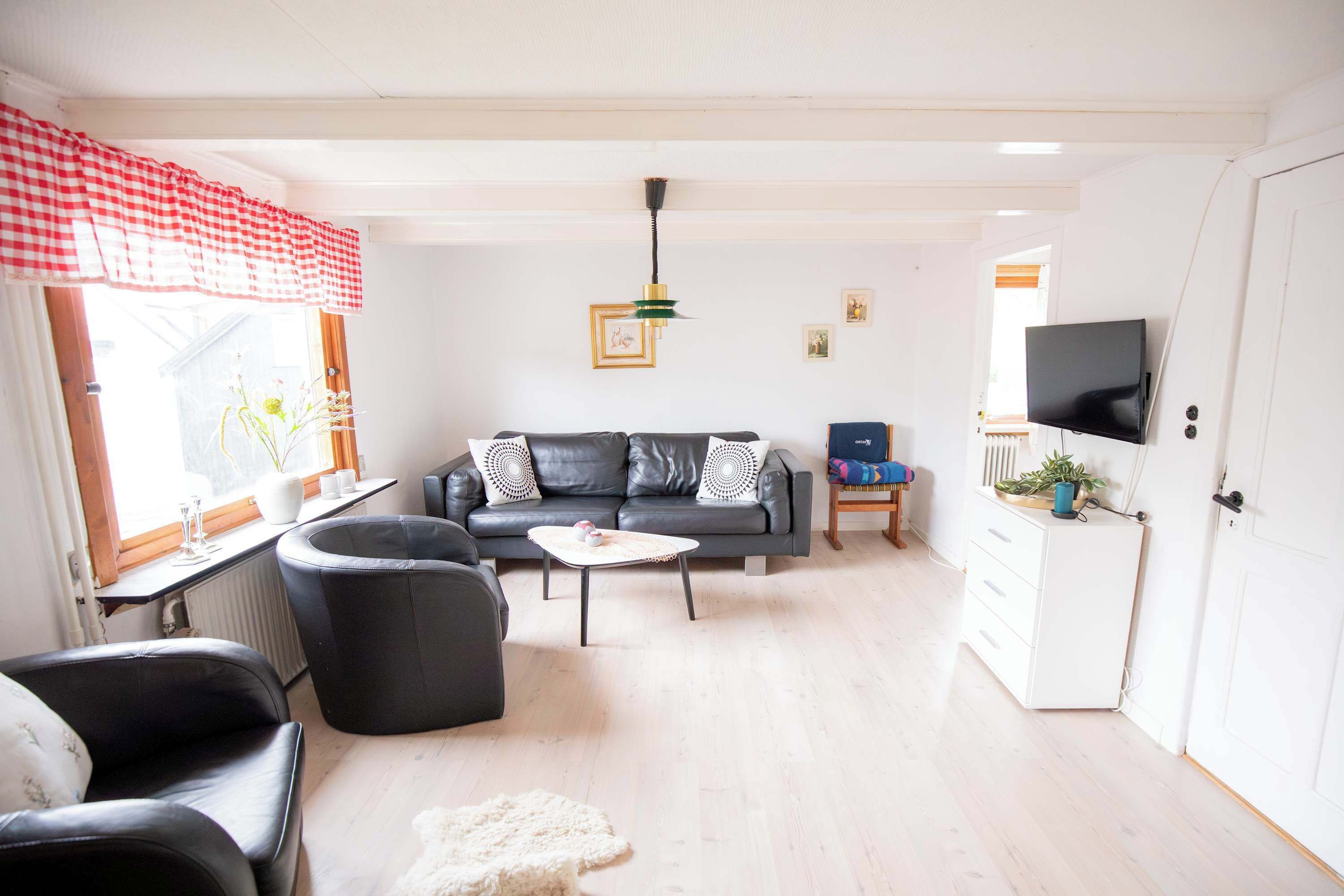 A living room with a sofa, chairs, a coffee table, a TV, and a window with a view.