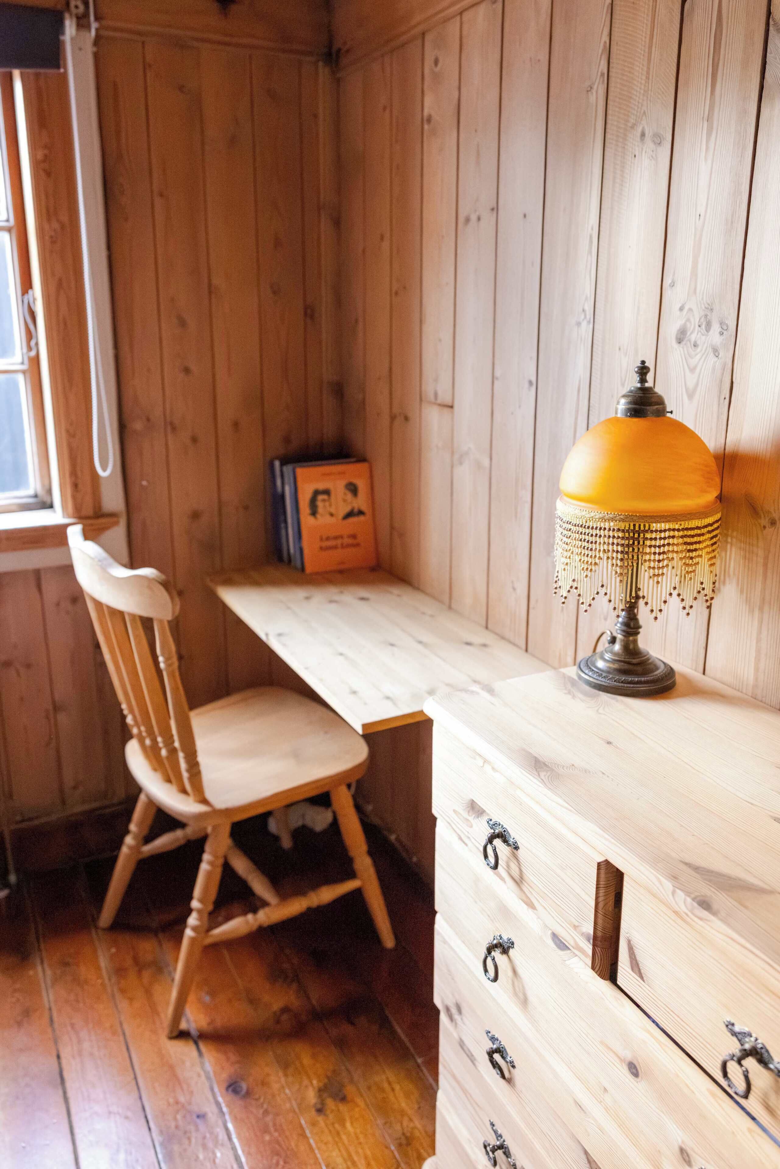 Un interior de madera con un escritorio, una silla y una lámpara.