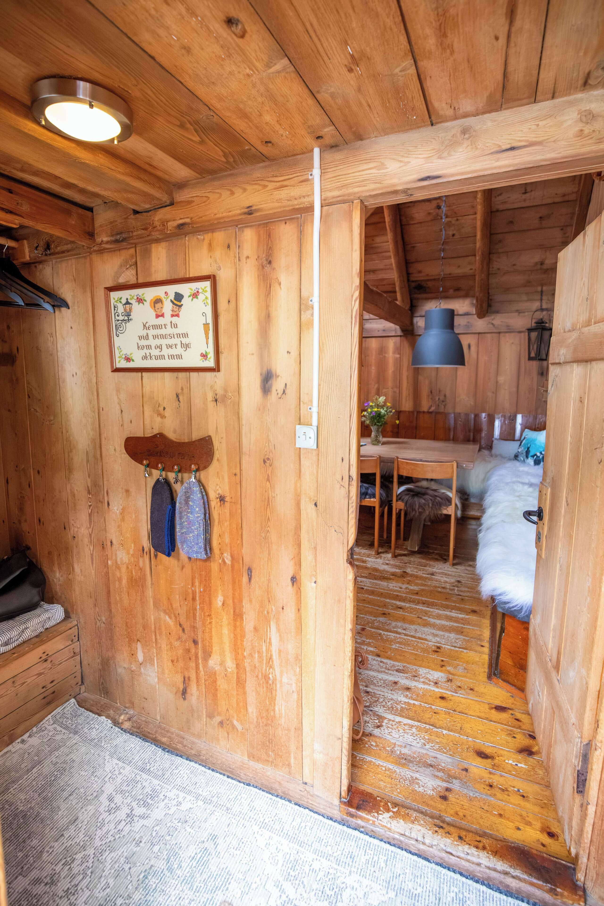 A wooden interior with a dining area, a kitchen, and a sleeping area with a bed.