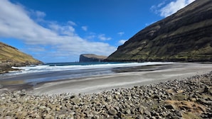 Eine Küstenlandschaft mit einem felsigen Strand, Wellen und einer Klippe.