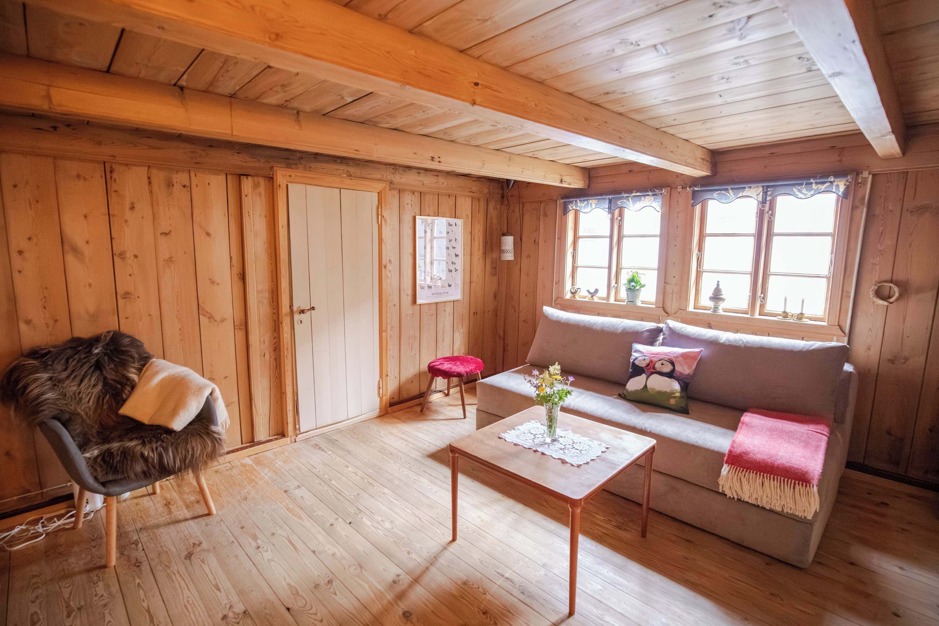 A cozy wooden interior with a sofa, a chair, and a small table.