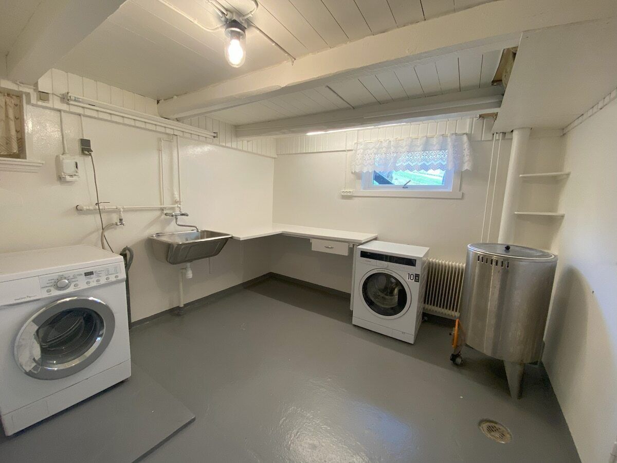 A laundry room with a washing machine, dryer, sink, and radiator.