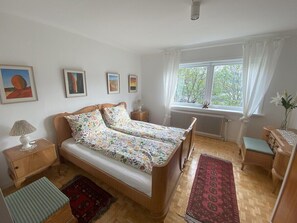 A bedroom with a double bed, two bedside tables, a window with curtains, and a radiator. - 5BR Charming Villa with Stunning Views - 9 guests (Vestmanna)