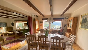 A dining area with a round table, wooden chairs, and a chandelier.