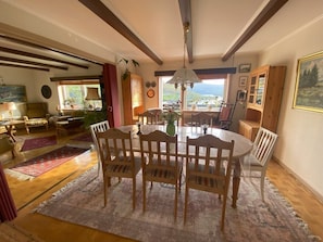 A dining area with a round table, wooden chairs, and a chandelier. - 5BR Charming Villa with Stunning Views - 9 guests (Vestmanna)