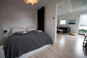 Een moderne slaapkamer met een groot bed, een nachtkastje, een lamp en een plafondarmatuur.