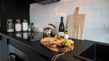 A kitchen counter with a charcuterie board, jars, a wine bottle, and a cutting board.