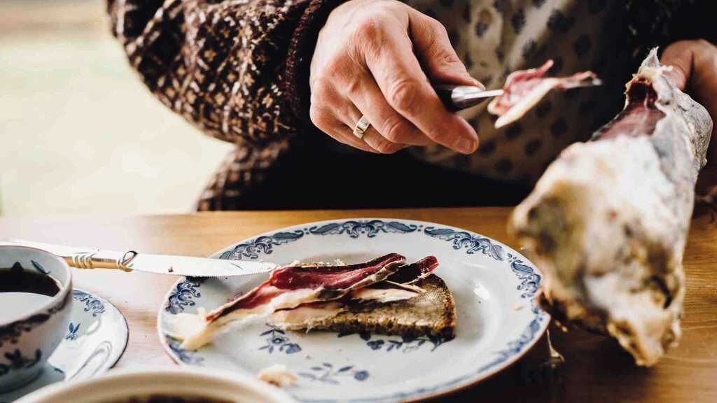 Una persona cortando una rebanada de carne en un plato con un cuchillo.