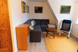 A cozy living room with a sectional sofa, a small round table, a rocking chair, and a bookshelf. - Cozy Apartment in a Quiet Area of Torshavn (Tórshavn)