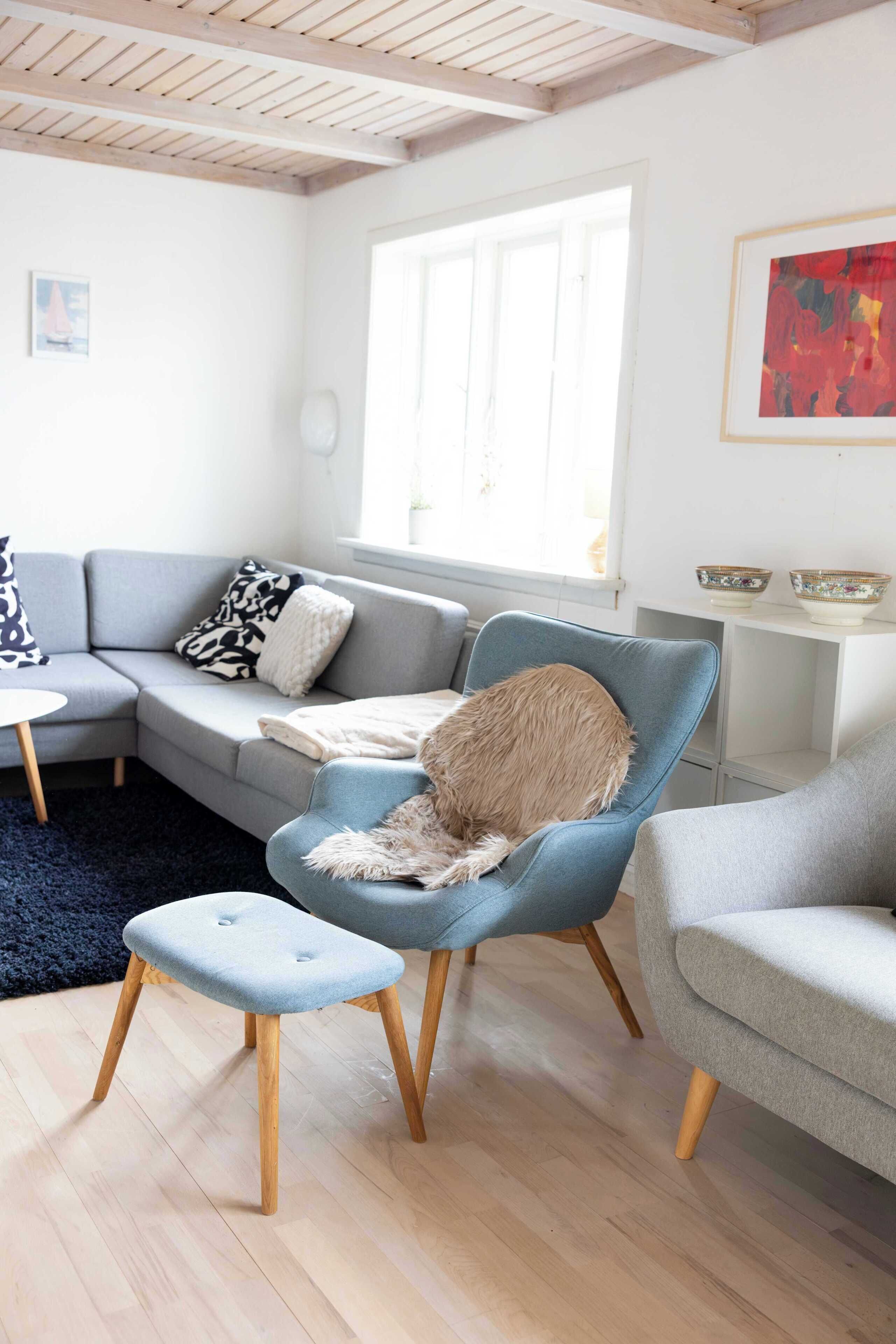 Ein modernes Wohnzimmer mit einem grauen Sofa, einem blauen Sessel und einem kleinen Tisch.