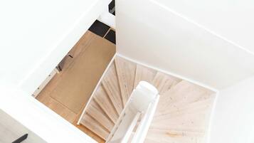 Vista aérea de una habitación moderna y minimalista con piso de madera, paredes blancas y una silla blanca.