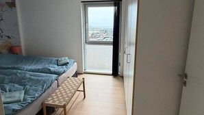 Ett sovrum med en säng, ett litet bord, en garderob och utsikt genom en dörr.