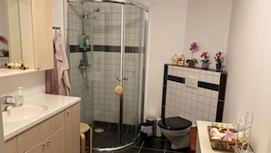 Ett badrum med dusch, toalett, handfat och en tvättställsmöbel med spegel.