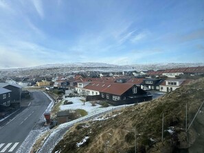 A residential area with houses, a road, and a hilly landscape in the background. - New Luxury Apartment With Panorama Views (Hoyvík)
