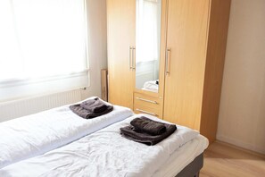 Une chambre avec un lit simple, une armoire et un miroir.