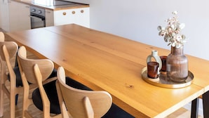Uma cozinha moderna com uma mesa de jantar de madeira, cadeiras e uma luminária pendente.