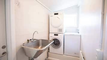 Un cuarto de lavandería con un lavabo, dos lavadoras apiladas y una ventana.