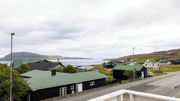 Un pueblo costero con casas, una carretera y vistas al mar y colinas.