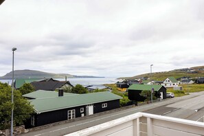 A coastal town with houses, a road, and a view of the sea and hills. - Torshavn Home with Views Near City Center (Tórshavn)