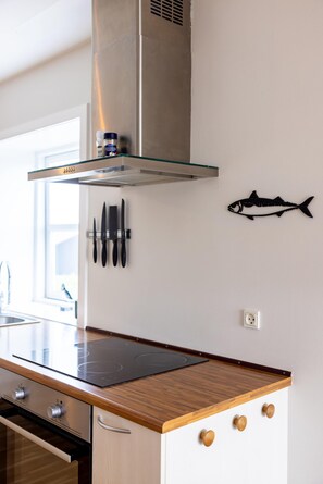 Una cocina con extractor de acero inoxidable, una decoración de pescado y un mueble para cuchillos.
