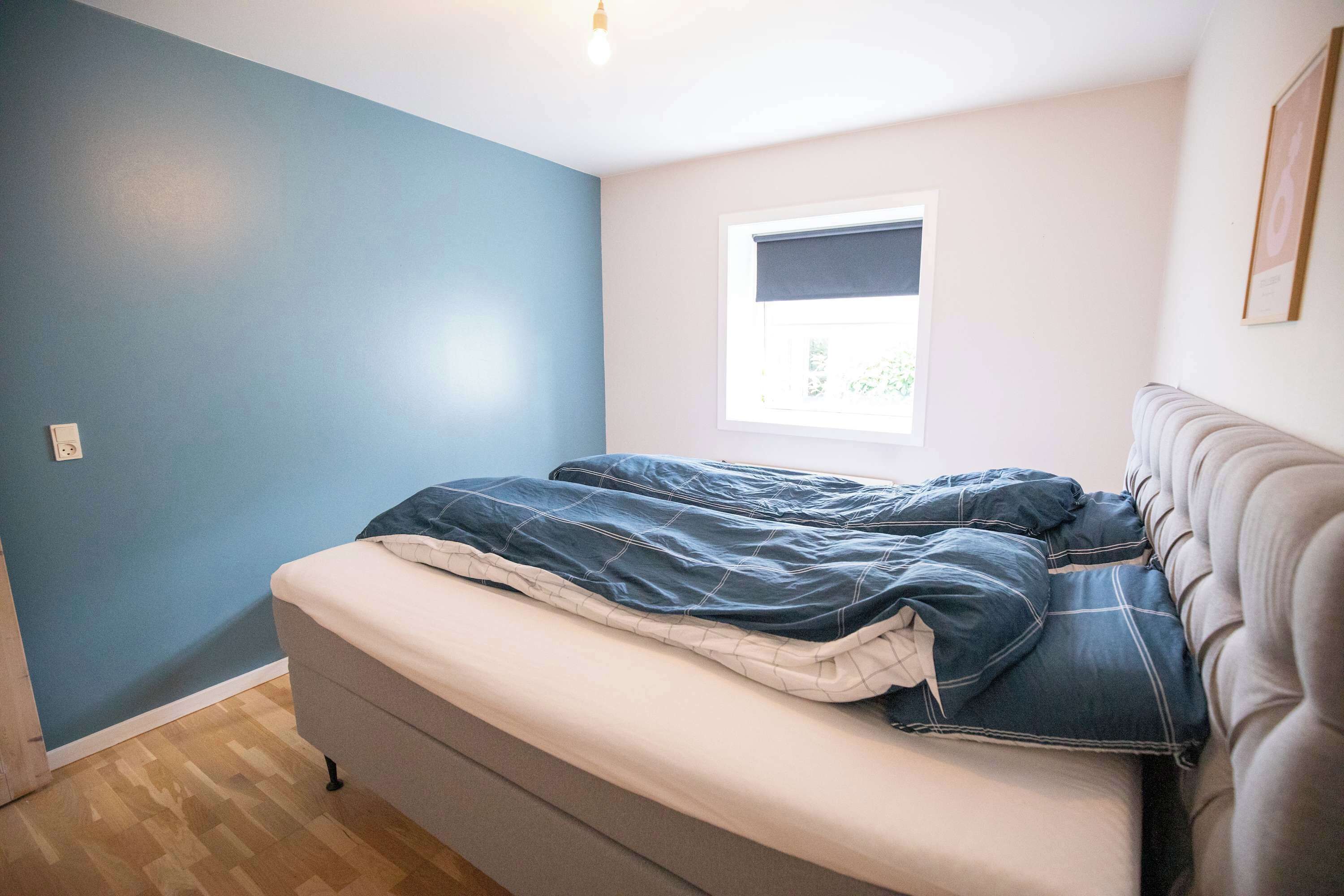 A bedroom with a bed, a window, and a light fixture.