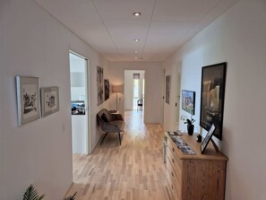 A hallway with wooden flooring, a sofa, and framed artwork on the walls. - Panoramic Fjord Views in Modern Kvivik House (Kvívík)