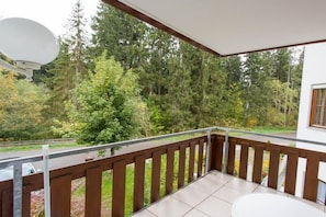 A balcony with a view of a forested area, a satellite dish, and a white building in the background. - House at Gutach No. 6 (Titisee-Neustadt)