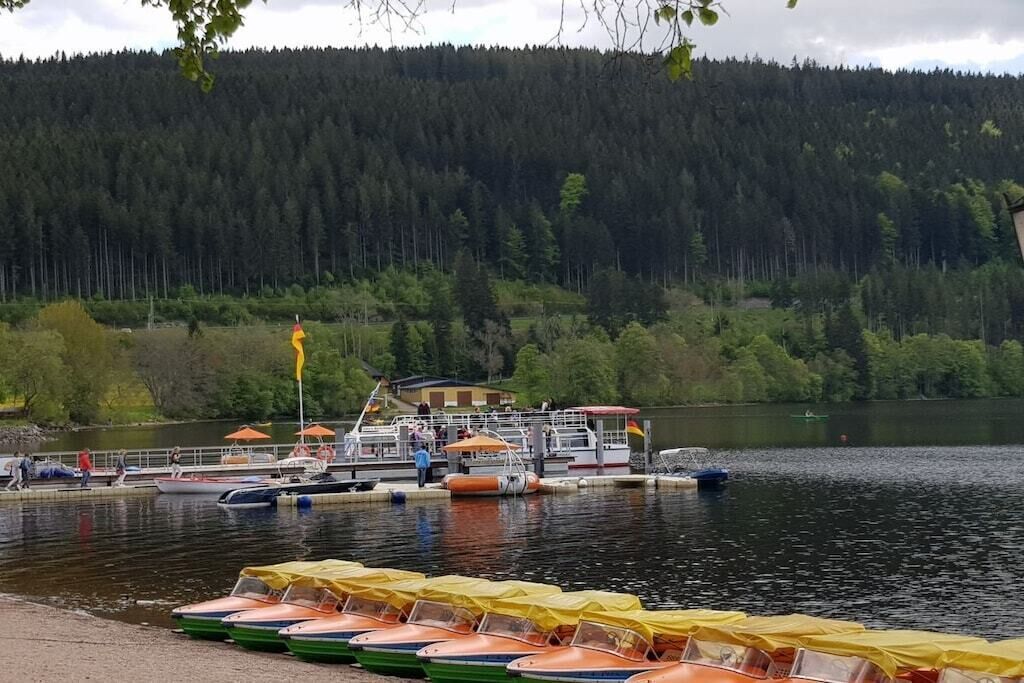A lakeside dock with boats, a flag, and a building in the background.