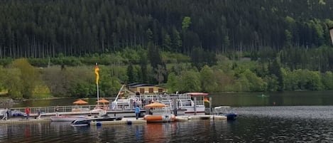 A lakeside dock with boats, a flag, and a building in the background.
