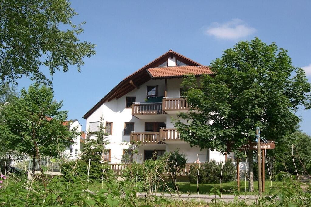A multi-story residential building with balconies, surrounded by greenery.