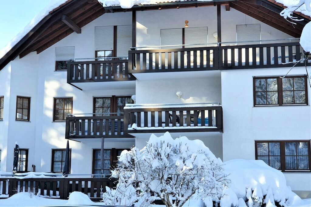 Un immeuble à plusieurs étages, doté de balcons et de fenêtres, et entouré d’un paysage enneigé.