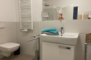 Un baño moderno con inodoro, lavabo y ducha.