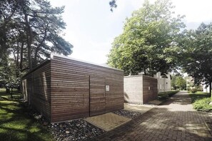 Ein Weg zu einem Gebäude mit Holzfassade und einem kleinen Eingang.