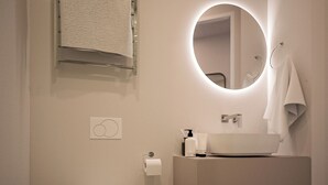 Un baño moderno con inodoro, lavamanos y espejo.