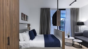 Ein modernes Hotelzimmer mit einem Bett, einer Couch, einem kleinen Tisch und einem Fernseher.