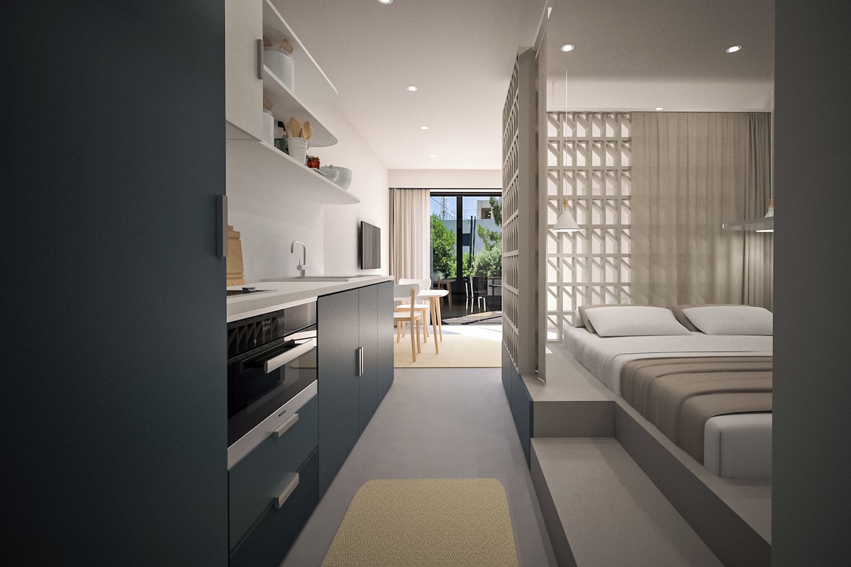 Habitació d'hotel moderna amb cuina americana, zona de menjador i dormitori amb finestra gran.