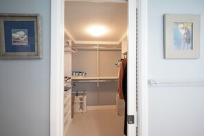 Um closet espaçoso com prateleiras, cabideiro e porta com porta-toalhas.