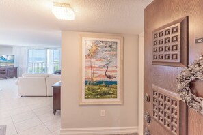 Uma sala de estar com uma janela grande, um quadro emoldurado na parede e uma porta com detalhe decorativo.