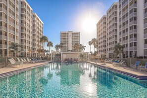 A swimming pool surrounded by multi-story buildings with balconies, clear blue water, and palm trees. - Beachfront 2B/2B Vacation Condo at Creciente w/Million $$$ View! (Fort Myers Beach)