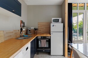 A compact kitchen with a microwave, oven, and sink. - Holiday Home 'L'ancien Atelier' with Private Terrace, Wi-Fi and Air Conditioning (Muides-sur-Loire)
