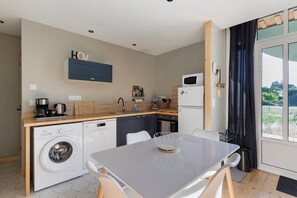 A compact kitchen with a washing machine, a coffee maker, and a microwave. - Holiday Home 'L'ancien Atelier' with Private Terrace, Wi-Fi and Air Conditioning (Muides-sur-Loire)