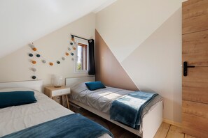 A bedroom with two beds, a bedside table, a lamp, a window with curtains, and a wall-mounted shelf. - Holiday Home 'L'ancien Atelier' with Private Terrace, Wi-Fi and Air Conditioning (Muides-sur-Loire)