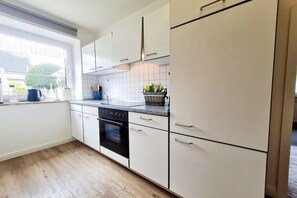 Eine moderne Küche mit weißen Schränken, einem eingebauten Backofen und einem Fenster, das für natürliches Licht sorgt.