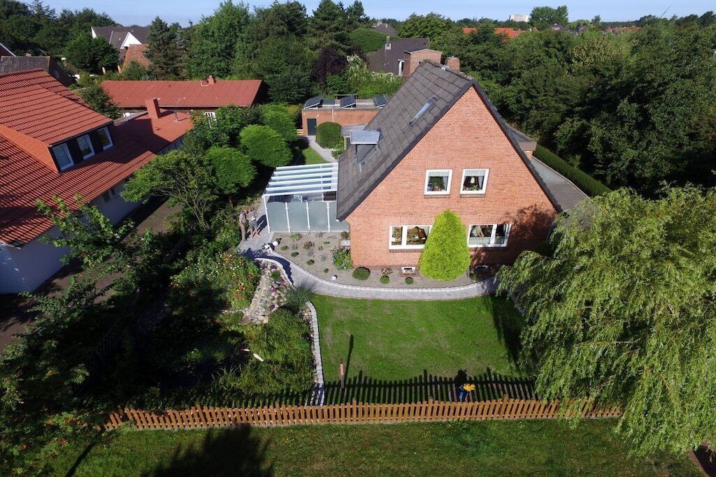 Ein Wohngebiet mit einem markanten Haus, das ein geneigtes Dach, einen Vorgarten und einen Holzzaun hat.