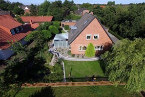 Ein Wohngebiet mit einem markanten Haus, das ein geneigtes Dach, einen Vorgarten und einen Holzzaun hat.