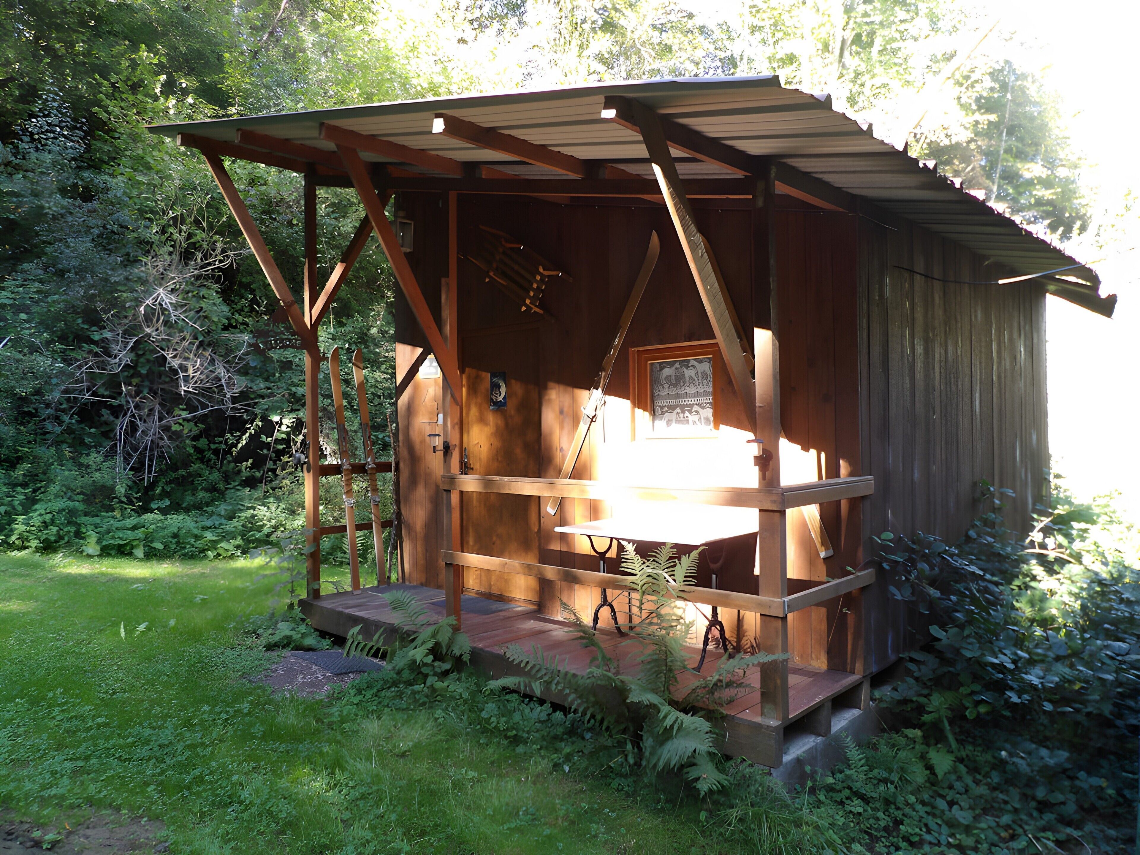 A wooden cabin with a porch, surrounded by greenery.